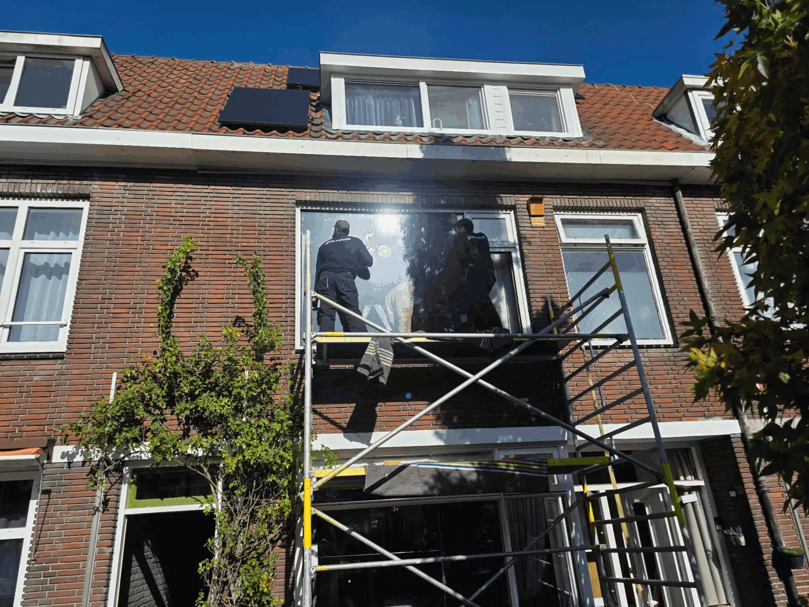 Monteurs van Glasfixer plaatsen dubbelglas op de eerste verdieping vanaf een steiger